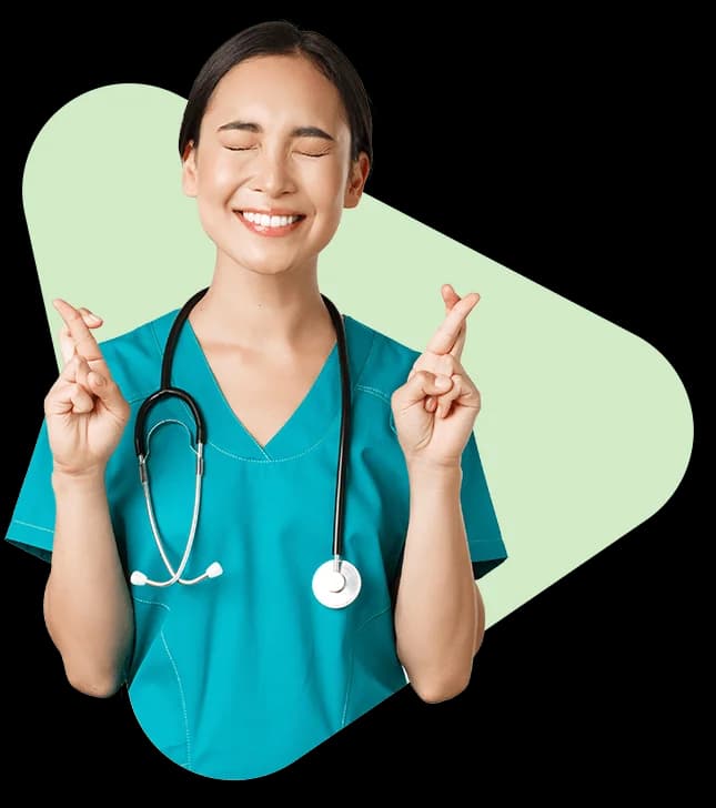 Medical student in scrubs with fingers crossed, smiling